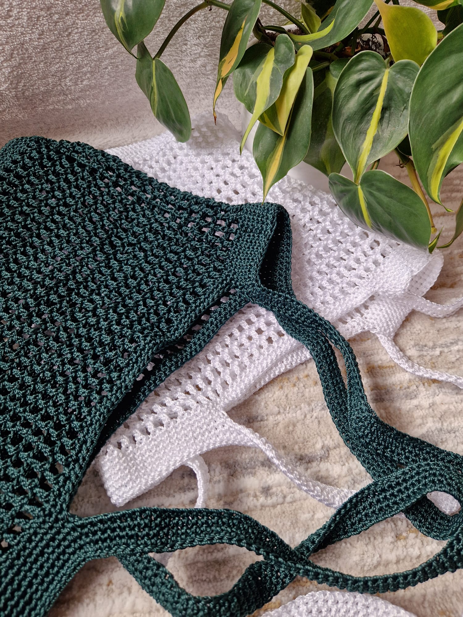 White and green Breezy Market Crochet Tote Bags stacked flat to show their size, shape, and knit pattern.