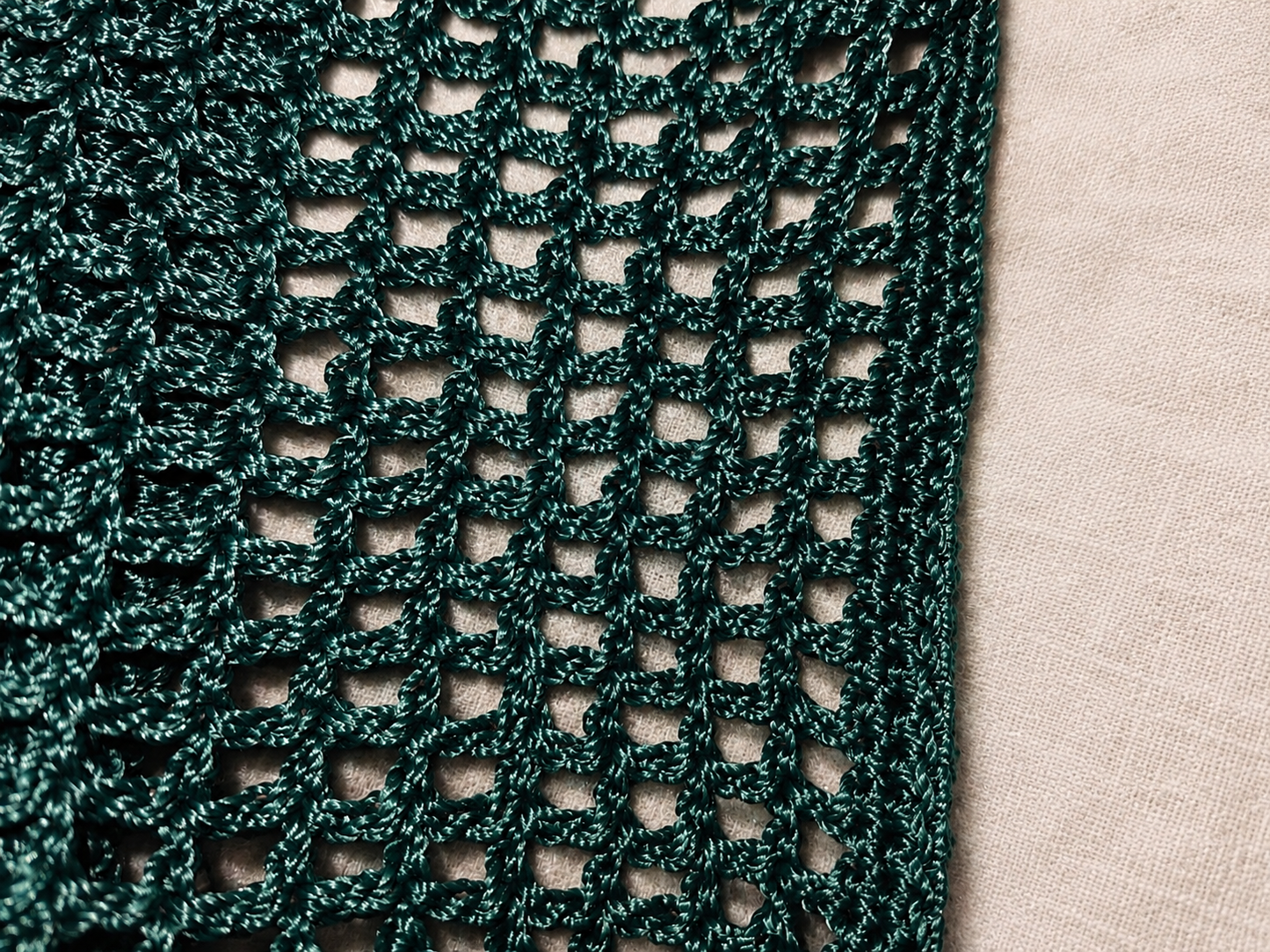 Close-up of a green knitted fabric with a beige background