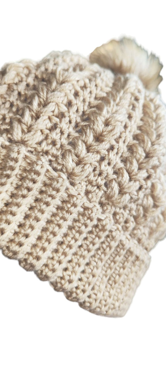 Flat lay of the Cozy Knit Pom-Pom Beanie in beige showing its ribbed texture, round shape, and soft pom detail.