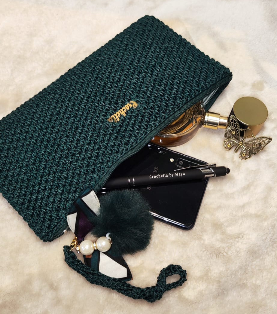Angled shot of the green clutch with geometric charm and zipper.