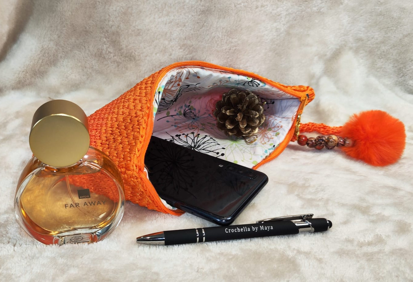 Flat lay of the orange clutch showing the full body and crochet finish