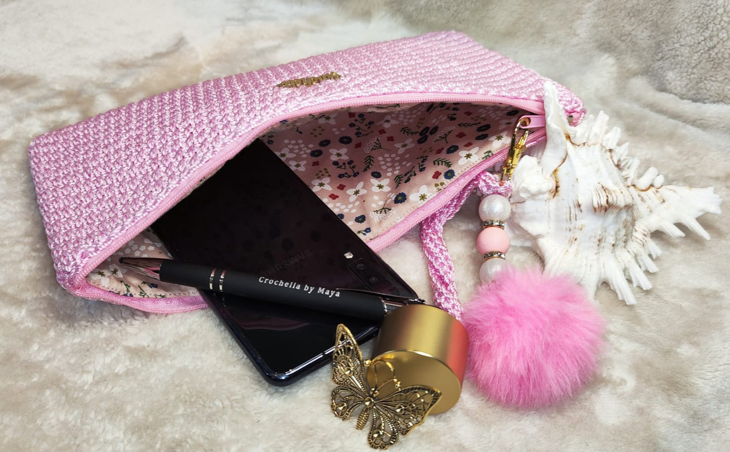 Detail shot of the pink clutch’s stitching and charm accent.