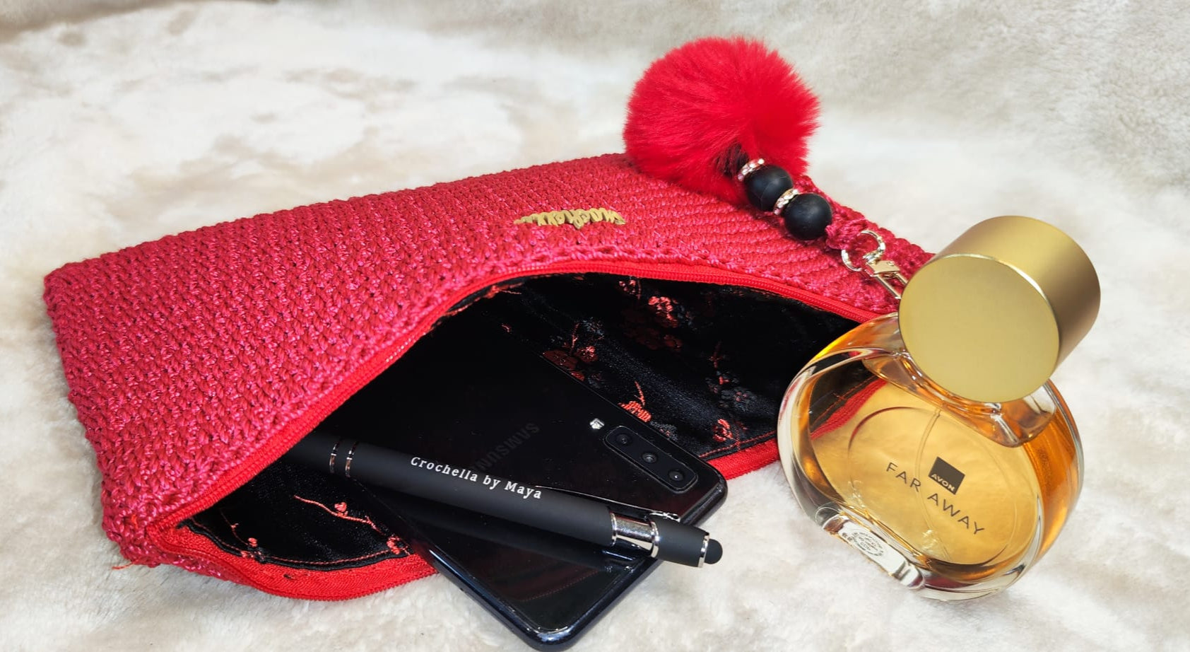 Close-up of the red clutch featuring the logo and matching charm.