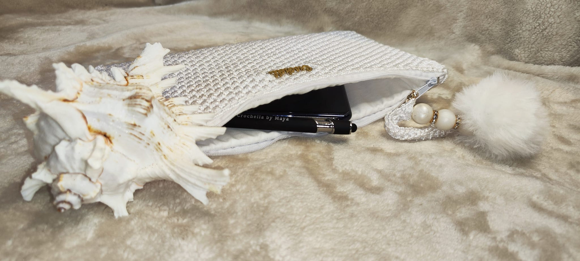 Side view of the white Crochella Luxe Clutch highlighting texture and charm detail.