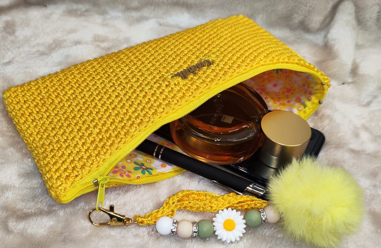 Detailed texture shot of the yellow clutch with crochet pattern and gold zipper.