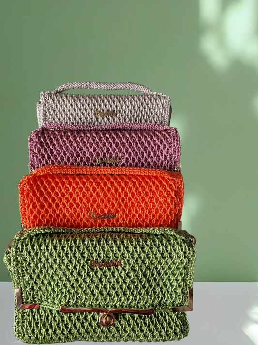 Four stacked Diamond Luxe Crochet Bags in beige, pink, orange, and green, displayed against a soft green background.
