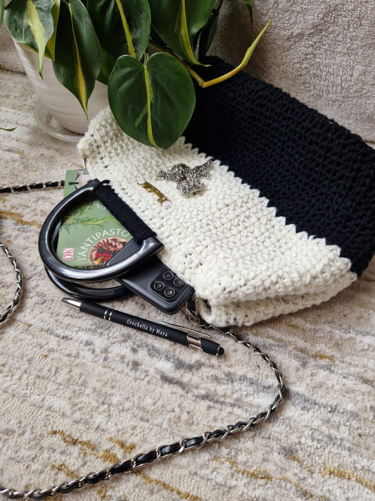 Angled view of the black and white Elegance Bow Handbag highlighting its sleek silhouette and elegant design.