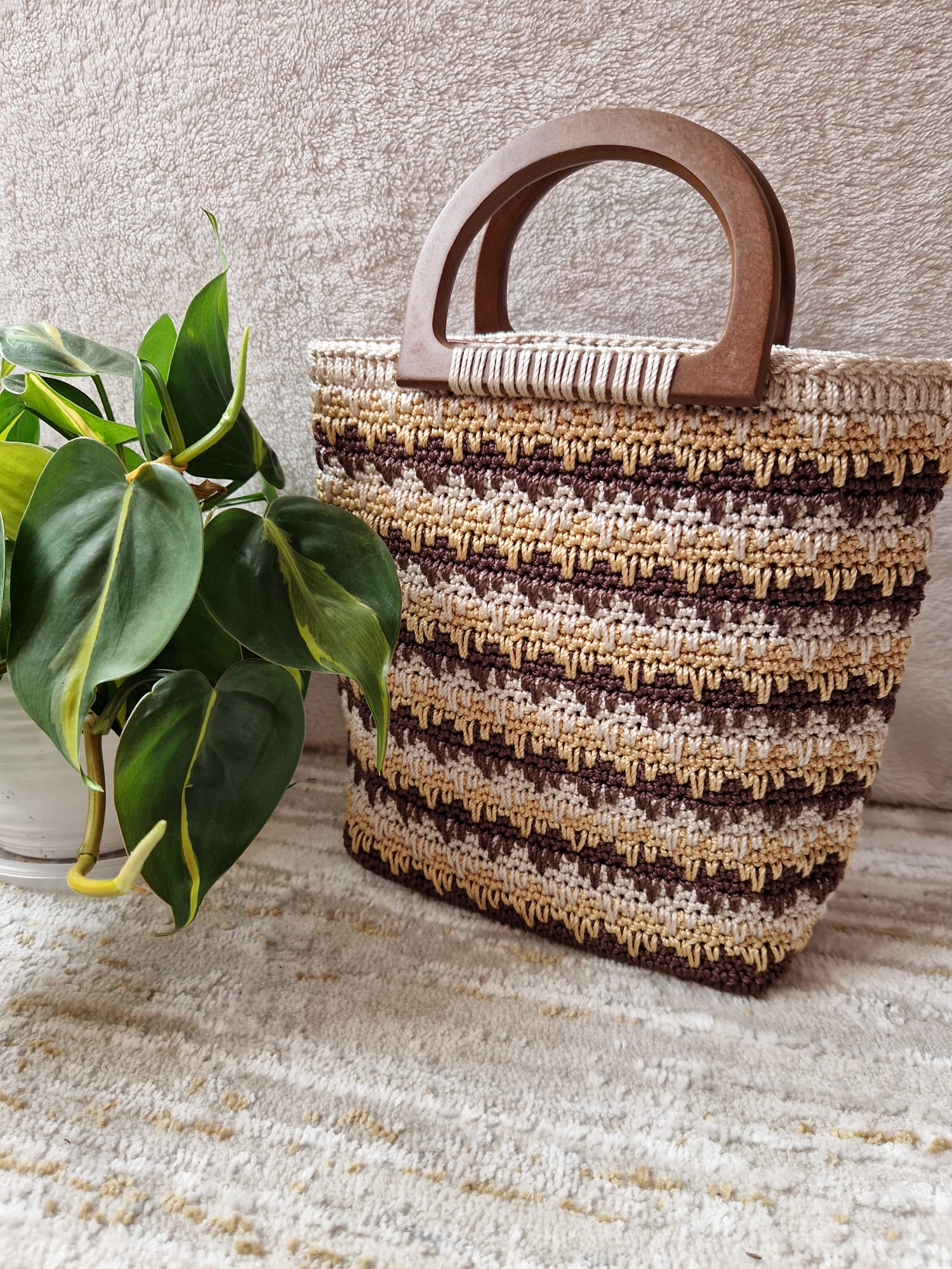 Caramel Twist Crochet Handbag in soft beige and brown yarns, detailed with a wooden handle and subtle shimmer.