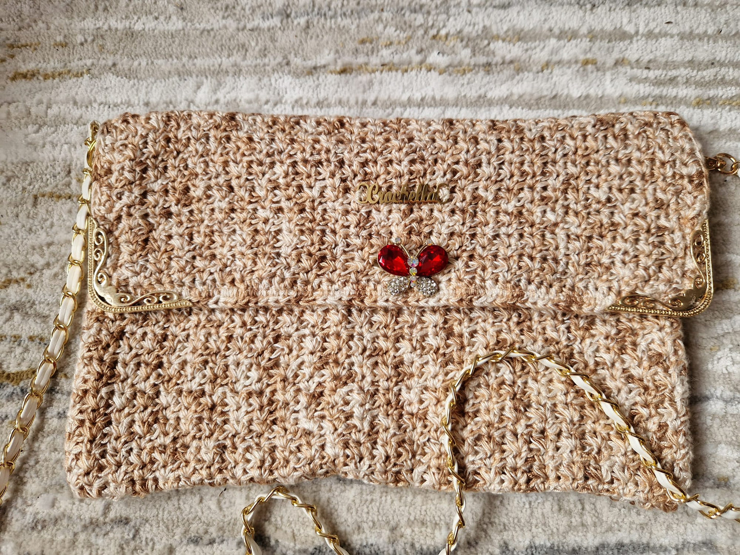 Front-facing view of the Golden Elegance Crochet Clutch showcasing its textured pattern, butterfly charm, and gold hardware.