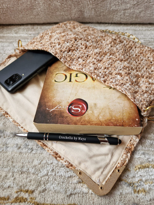 The Golden Elegance Crochet Clutch styled in a cozy setting with soft textures and greenery for a classy, romantic vibe.
