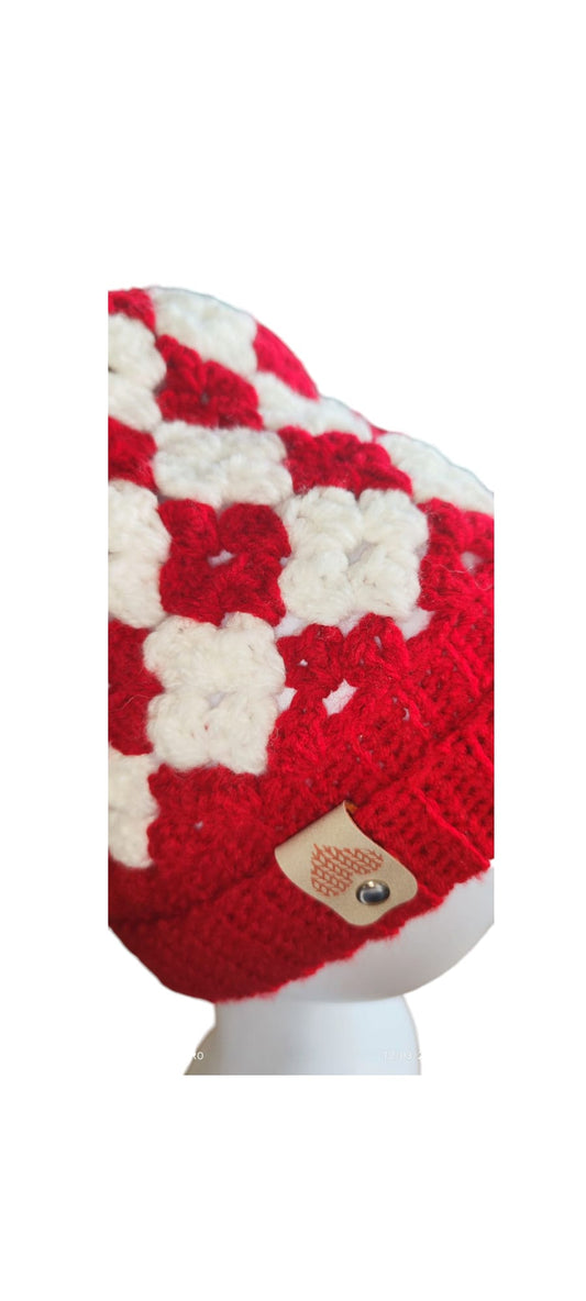 Close-up view of the red and white beanie highlighting granny square pattern, ribbed band, and soft yarn texture.