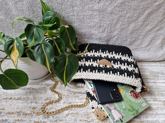 Angled view of the Monochrome Elegance Handbag highlighting its structured form, gold-toned chain, and refined color palette.