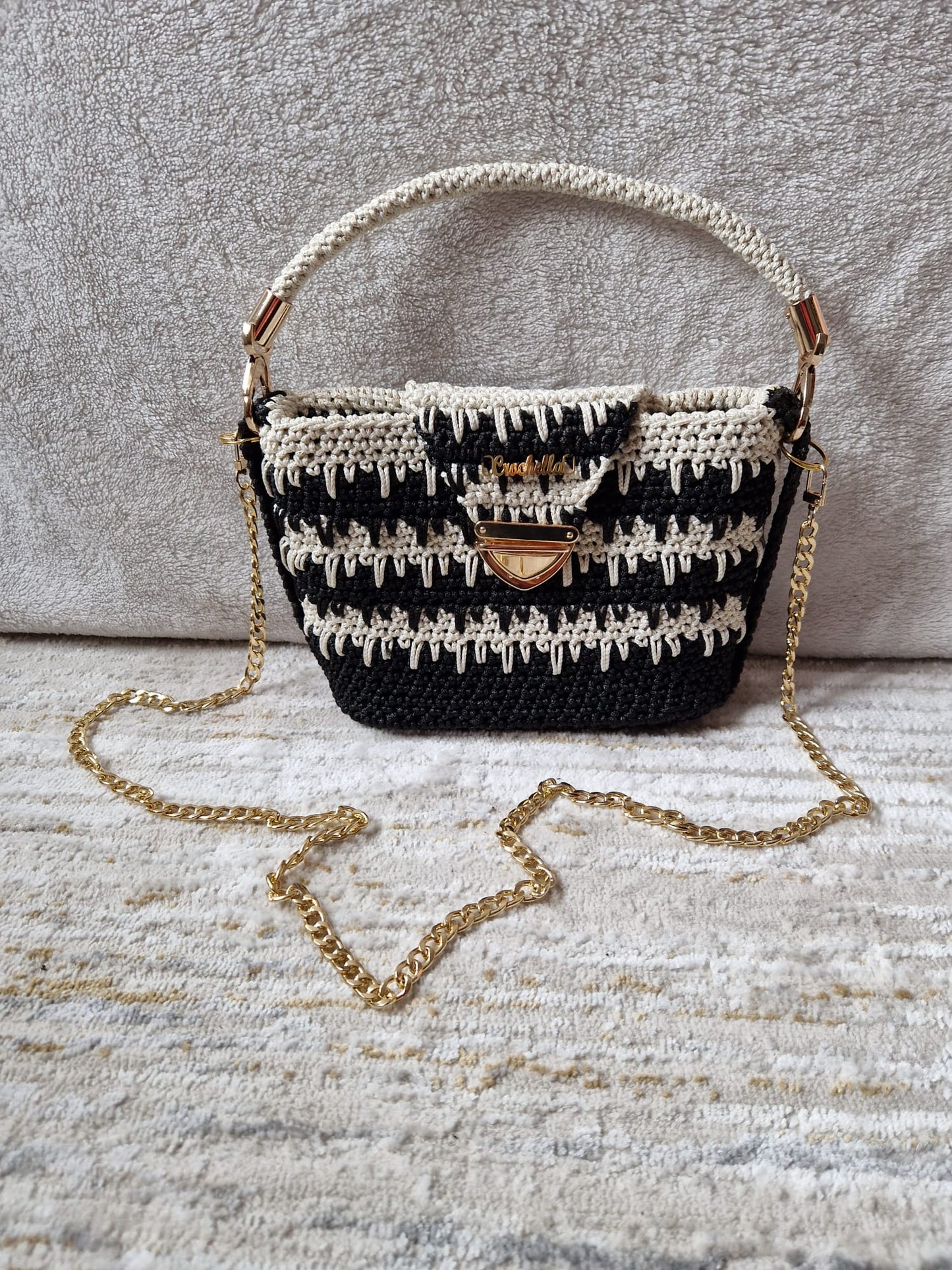 Monochrome Elegance Crochet Handbag in black and ivory with a bold textured stitch pattern, top handle, and gold chain strap.