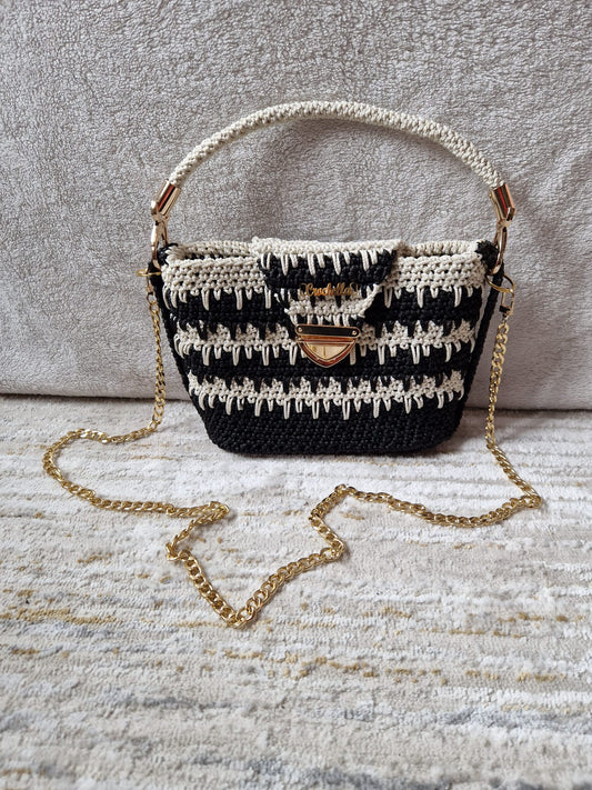 Monochrome Elegance Crochet Handbag in black and ivory with a bold textured stitch pattern, top handle, and gold chain strap.