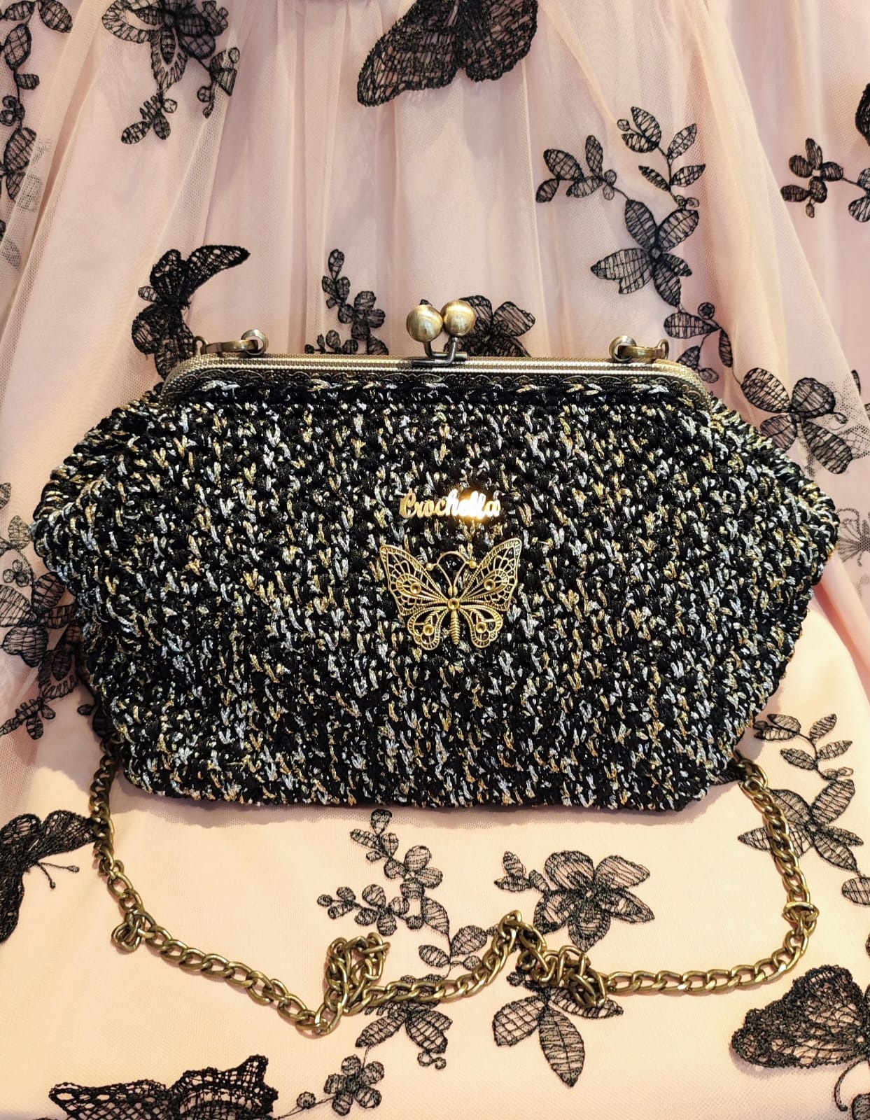 Midnight Bloom handbag in deep black with gold threading and a statement butterfly charm, styled against a lace backdrop.