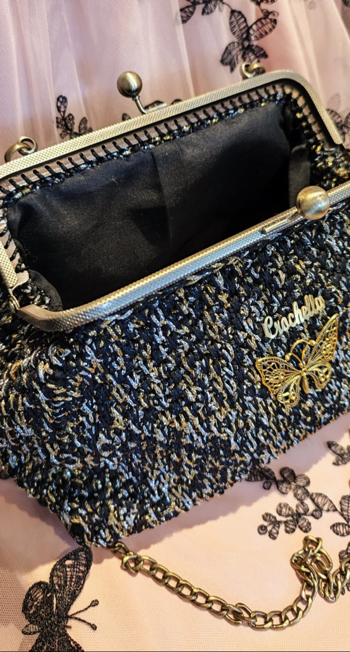Close-up of the butterfly logo and shimmering black-and-gold crochet stitch on the Midnight Bloom handbag.