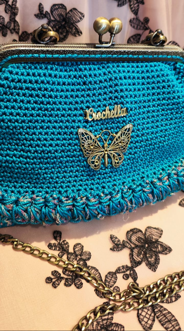 Side view of the Royal Teal crochet handbag with its gold chain strap and classic kiss-lock closure.