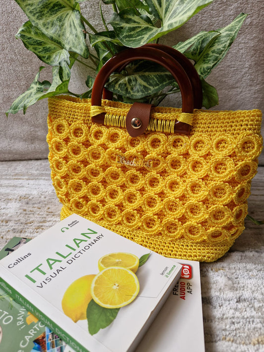 Front view of the Sunburst Bloom Handmade Crochet Handbag with sunny yellow circle pattern and rich wooden handles.