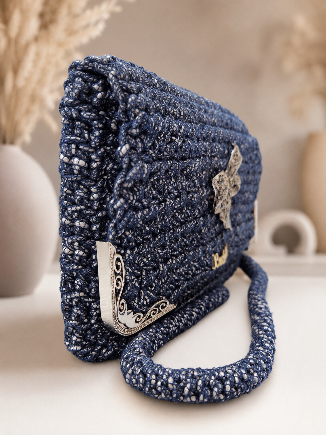 Blue textured handbag with decorative elements on a neutral background