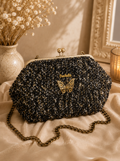 Black textured handbag with gold butterfly design and 'Bucheli' branding on a light fabric surface.