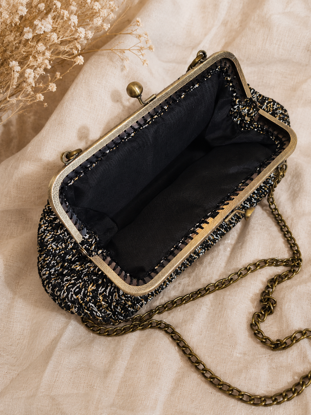 Vintage-style handbag with chain strap on a textured fabric background