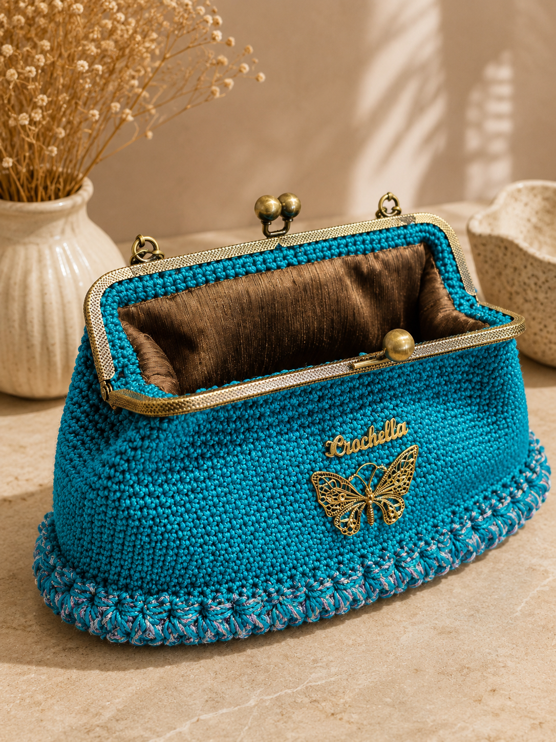 Blue knitted purse with gold butterfly charm on a neutral background