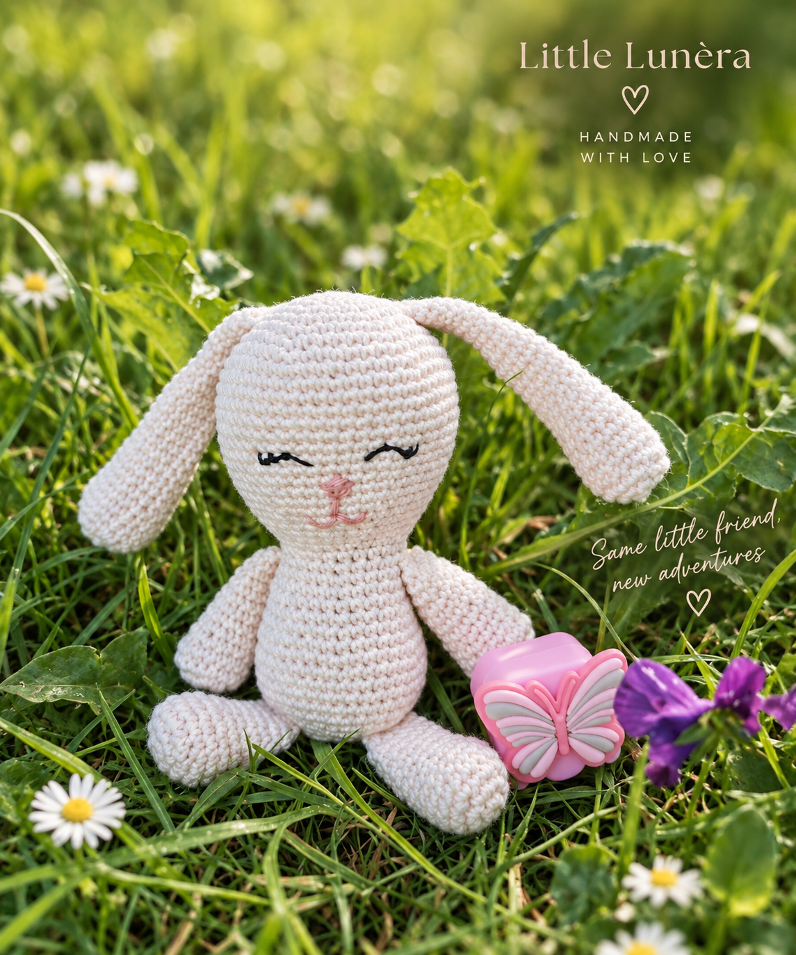 A crocheted bunny plush toy sits in green grass with daisies and purple flowers. The bunny is cream-colored with embroidered closed eyes, pink nose, and long floppy ears.