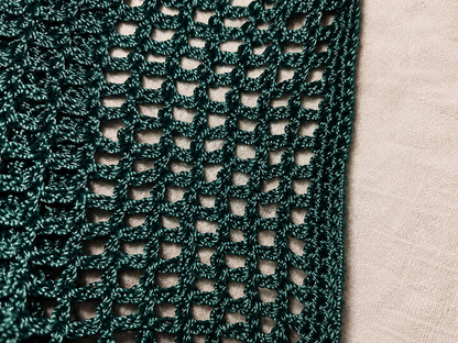 Close-up of a green knitted fabric with a beige background