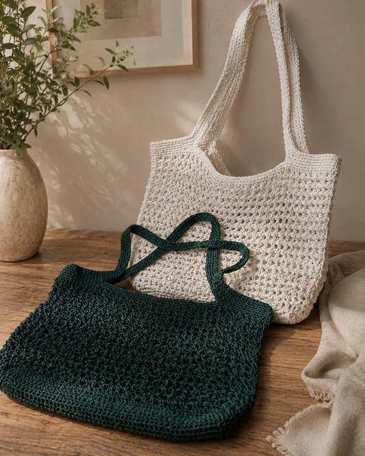 Two crocheted bags, one green and one white, on a wooden surface with a neutral background.