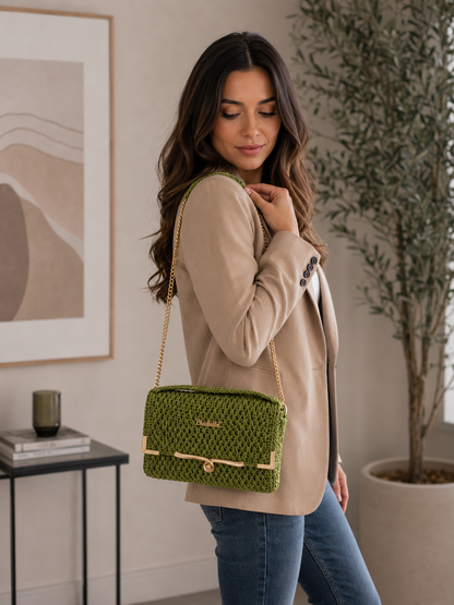 Woman holding a green handbag indoors with a neutral background