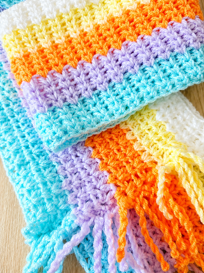 Colorful crocheted blanket with a striped pattern on a wooden surface