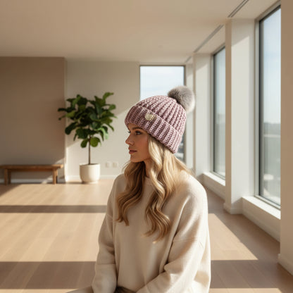 Soft Lavender handmade crochet beanie with gray faux-fur pom-pom, displayed on a mannequin with a winter-themed backdrop.
